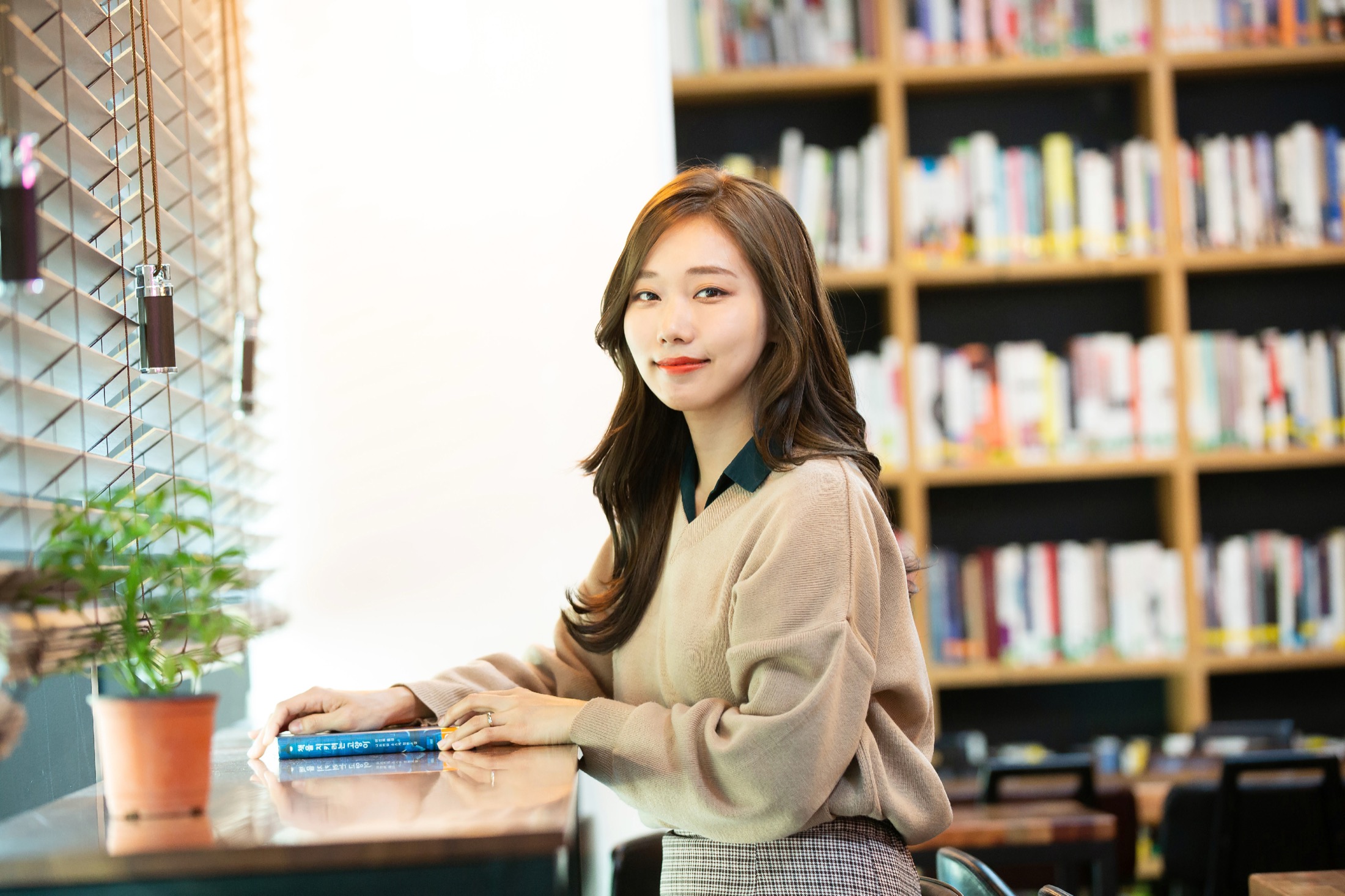 서재 책장을 배경으로 책을 앞에 두고 미소 짓는 정은지.