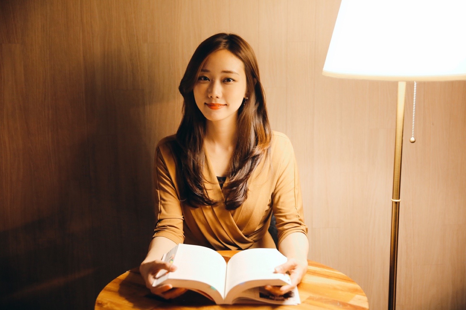 따뜻한 조명 아래 책상에 앉아 편안한 표정으로 책을 읽는 정은지.