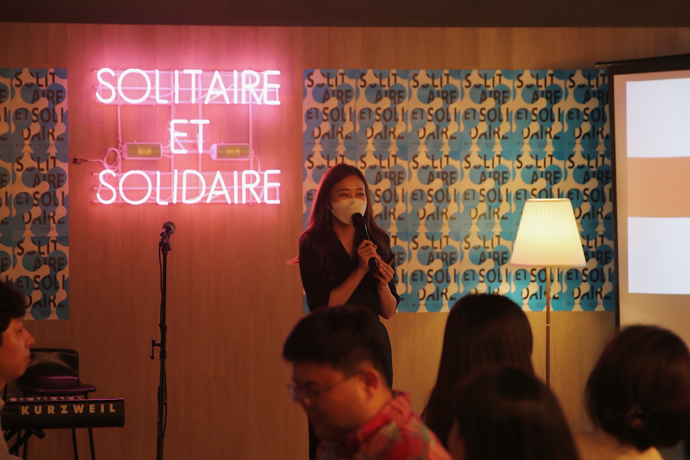 'SOLITAIRE ET SOLIDAIRE' 네온사인 앞에서 마이크를 들고 이야기하는 정은지.
